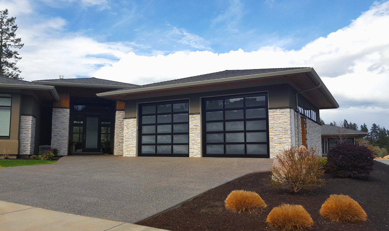 Modern home with two black-framed glass garage doors